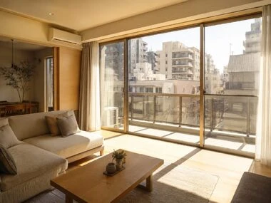 大きな窓から強い日差しが差し込み、室温が高くなっているマンションのリビングルーム